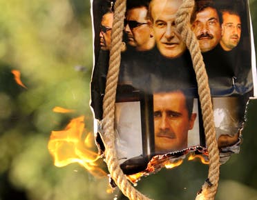 A makeshift gallows with a poster shows the pictures of former Syrian president Hafez al-Assad (top-C), his sons current President Bashar al-Assad (2nd L and bottom C) and Maher (L), their brother in-law General Assef Shawkat (2nd R) and businessman Rami Makhluf (R). (File photo: AFP)