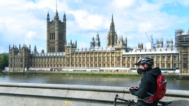 A man stands with his bike against the backdrop of the Houses of Parliament as the United Kingdom continues its lockdown to curb the spread of coronavirus, in London on May 1, 2020. (AP)
