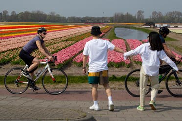A couple stops walking to observe social distancing from passing cyclists on the main road in Lisse, Netherlands. (AP)