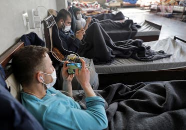 A Syrian man wearing a face mask plays a game on a mobile phone at a quarantine center in the town of Jisr al-Shughour in Idlib province, Syria April 30, 2020. (Reuters)