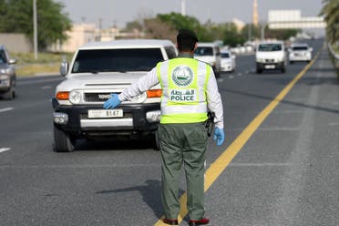 A policeman stops vehicles at a security checkpoint to examine passengers for exit permits, as people are only allowed essential travel due to a lockdown imposed by the UAE government as a measure during the COVID-19 coronavirus pandemic, in al-Khawaneej district of the gulf emirate of Dubai on April 9, 2020. (AFP)