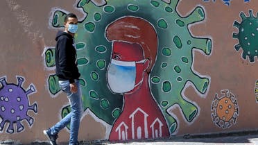 A Palestinians man wearing a face mask walks past a mural depicting the coronavirus COVID-19 coronavirus pandemic, in Gaza City. (File photo: AFP)