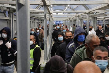 Palestinian laborers enter Israel through the Mitar checkpoint in the occupied West Bank city of Hebron, on May 3, 2020. (AFP)