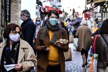A woman wearing a protective facemask walks in the Mouffetard street as she does her grocery shopping during the food market, on May 2, 2020 in Paris. (AFP)