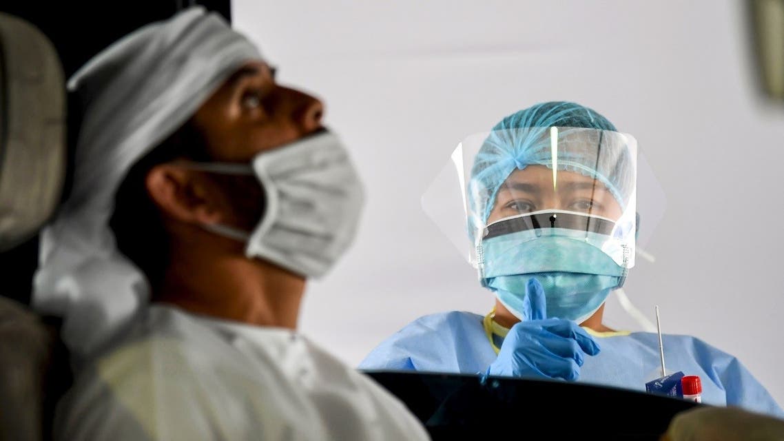 A medical staffer gives a thumbs-up gesture after obtaining a swab sample from a man inside a vehicle at a drive-through COVID-19 coronavirus testing centre in al-Khawaneej district of the gulf emirate of Dubai on April 9, 2020. (AFP)