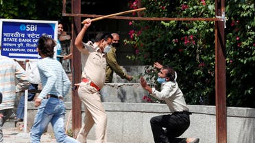 A police officer raises a baton at a man who, according to police, had broken the social distancing rule, outside a wine shop during an extended nationwide lockdown to slow the spread of the coronavirus disease (COVID-19), in New Delhi, India. (Reuters)