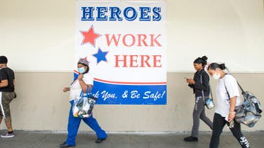 Employees walk by a sign Heroes Work Here outside of the Los Angeles USPS Plant on April 29, 2020, in Los Angeles, California.  (AFP)