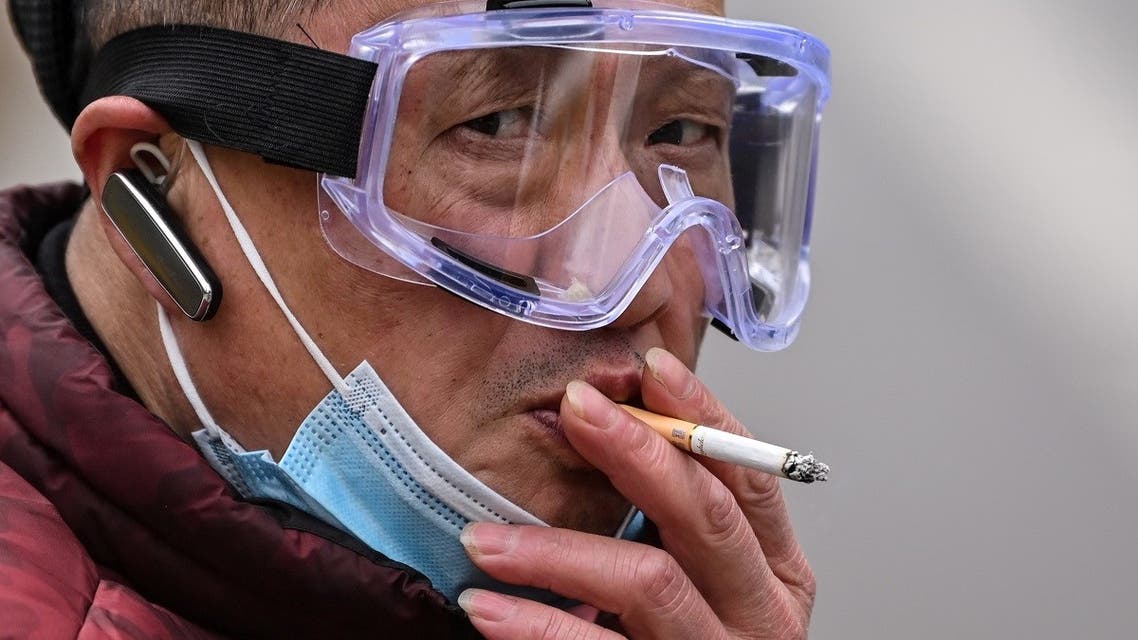 A man smokes a cigarette on his scooter in Wuhan, in China's central Hubei province on April 10, 2020. (AFP)