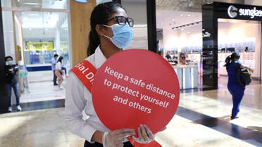 A woman wearing a protective face mask and gloves holds a sign at Mall of the Emirates after the UAE government eased a curfew and allowed stores to reopen, following the outbreak of the coronavirus in Dubai, United Arab Emirates, May 5, 2020. (Reuters)