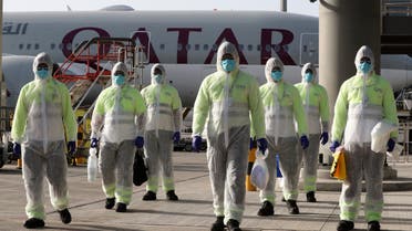 employees of Qatar Aviation Services (QAS), wearing protective gear as a safety measure during the COVID-19 coronavirus pandemic, walk along the tarmac after sanitising an aircraft at Hamad International Airport. (AFP)