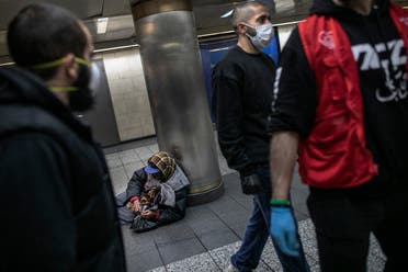 A homeless man in New York’s Penn station opens a packet of food given to him by Hamza Deib, owner of Taheni Mediterranean Grill, center, and Mohammed Widdi, Coordinator at Muslims Giving Back, on Friday, May 1, 2020. (AP)