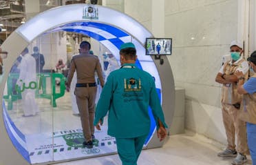 An officer and a worker pass through the self-sanitzation gates at the entrance of the Grand Mosque in Mecca. (Twitter)