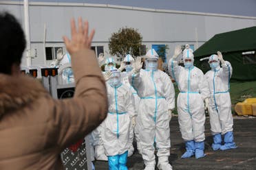 Medical personnel in protective suits wave hands to a patient who is discharged from the Leishenshan Hospital after recovering from the novel coronavirus, in Wuhan, China on March 1, 2020. (Reuters)