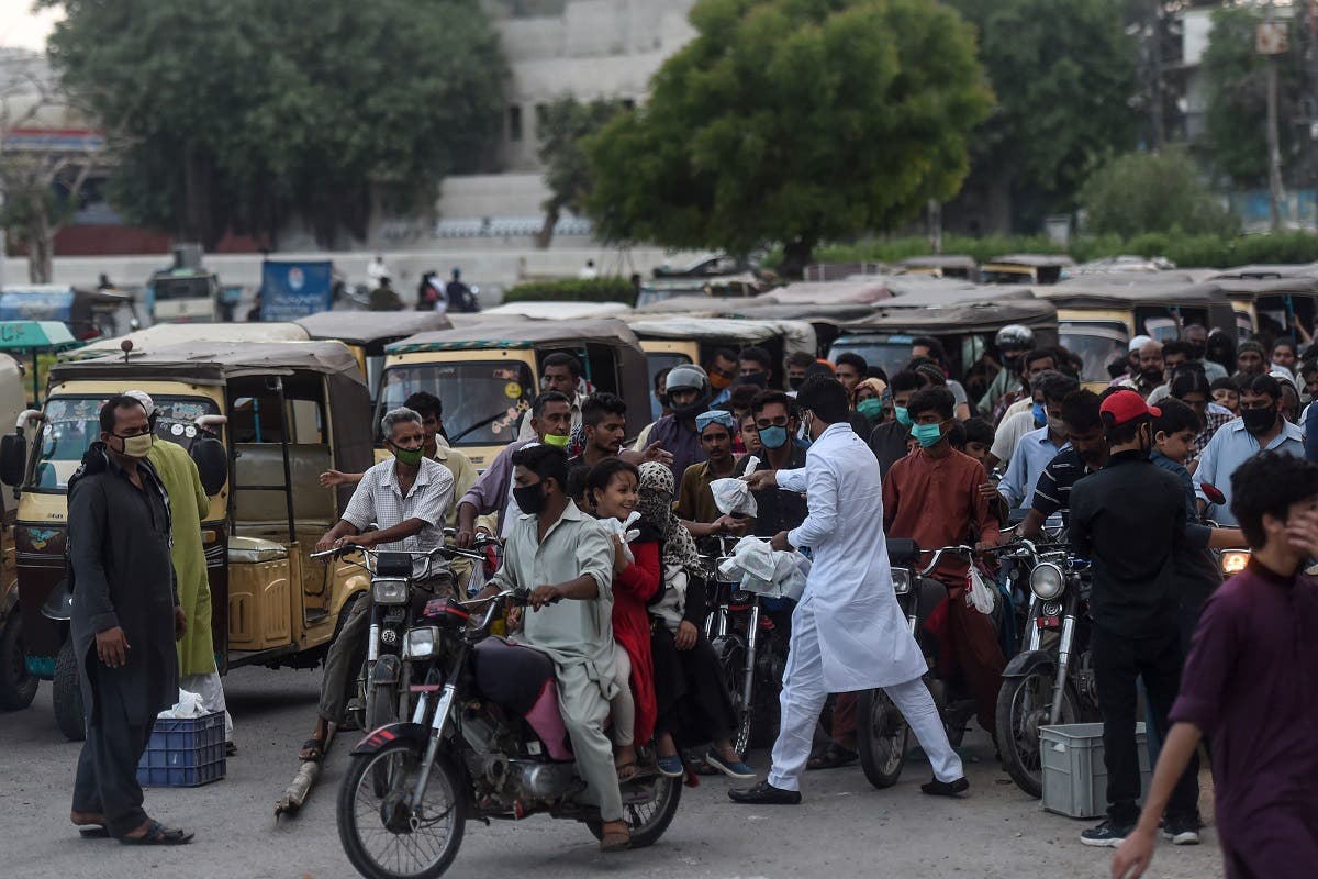 A man (in white) distributes food to people in need during a road traffic after the government eased the nationwide lockdown imposed as a preventive measure against the COVID-19 coronavirus, in Karachi on May 9, 2020. (AFP)