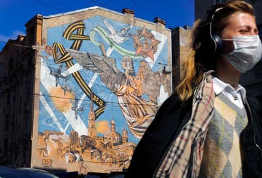 A woman wearing a face mask to protect against coronavirus walks past a graffiti dedicated to the victory of the Soviet Union in the World War II, in St. Petersburg, Russia on May 4, 2020. (AP)