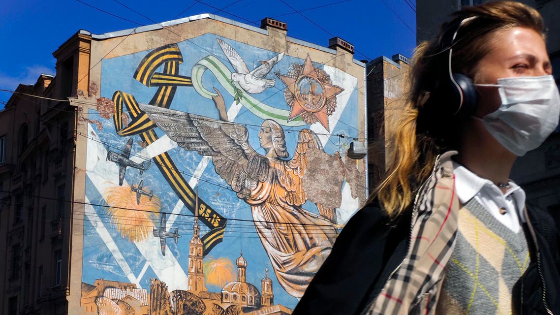 A woman wearing a face mask to protect against coronavirus walks past a graffiti dedicated to the victory of the Soviet Union in the World War II, in St. Petersburg, Russia on May 4, 2020. (AP)