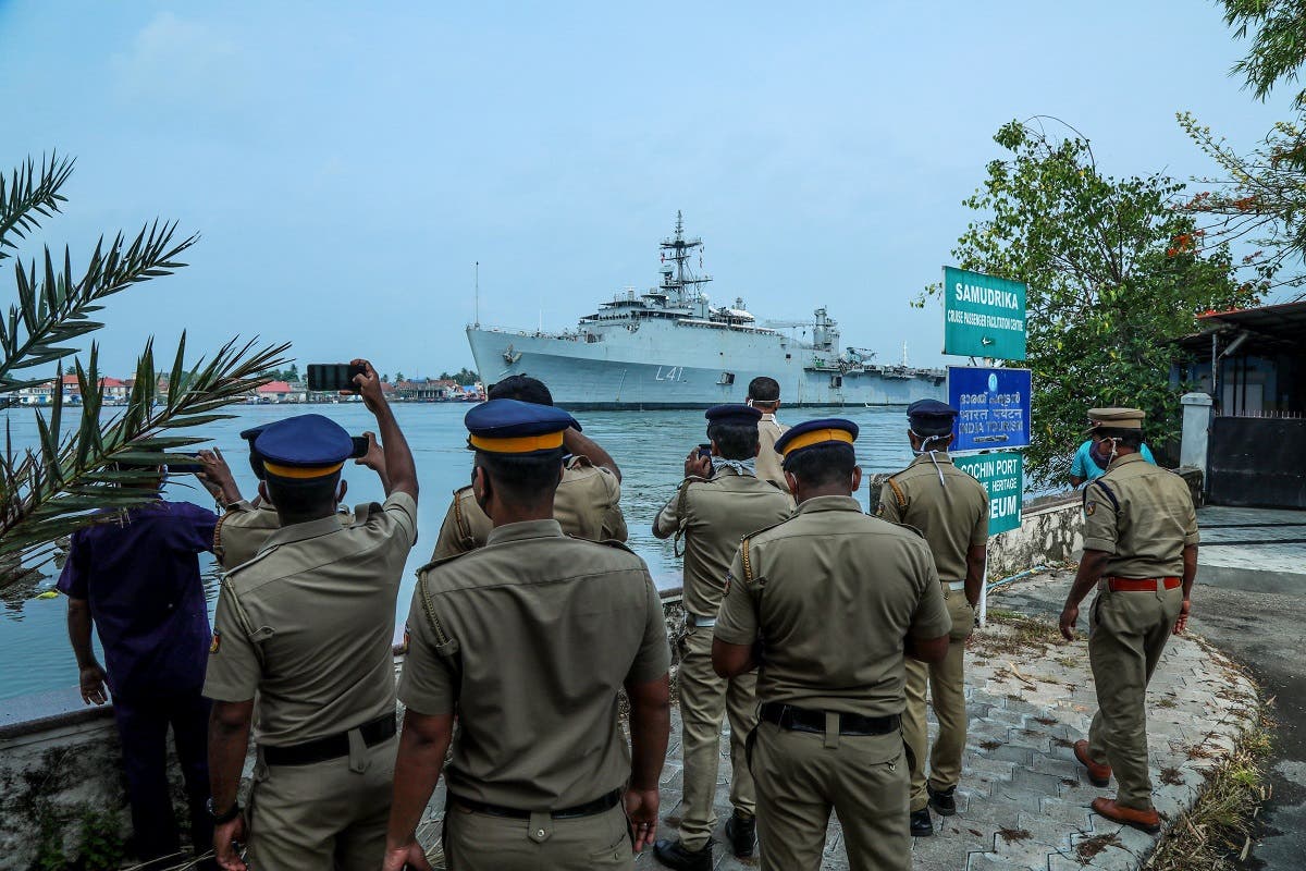 Kerala police personnel watch and take photos as the INS Jalashwa ship enters the Cochin port carrying Indian citizens who were stranded in Maldives, in Kochi in the south Indian state of Kerala on May 10, 2020. (AFP)
