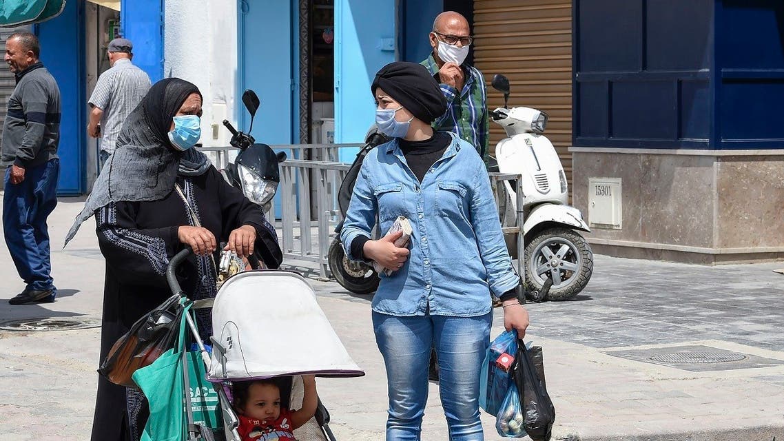 Tunisians wearing protective masks walk in the Kram area of the capital Tunis on May 8, 2020, as authorities begin a gradual sector and region-based process to mitigate lockdown measures. (AFP)
