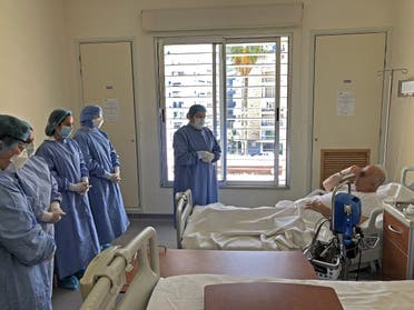 A picture taken by a nurse on April 9, 2020 at the Hotel Dieu de France Hospital, shows a colleague joining a patient in prayer in the coronavirus section of the hospital in Beirut’s eastern suburbs. (AFP)