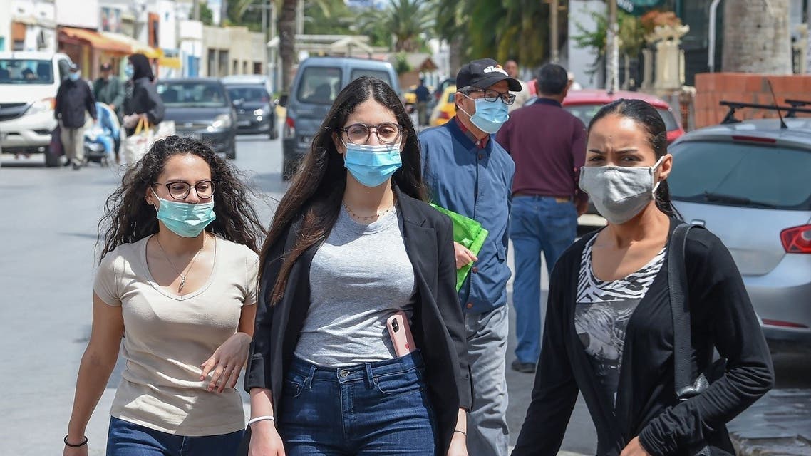 Tunisians wearing protective masks amid the COVID-19 pandemic walk by on a street in the Kram area of the capital Tunis on May 8, 2020. (AFP)