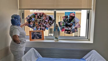 A picture taken by a nurse on April 30, 2020 at the Hotel Dieu de France Hospital, shows a colleague staring at family pictures displayed on a window behind a statue of the Virgin Mary in the coronavirus section of the hospital. (AFP)
