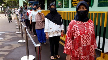 FILE PHOTO: People wearing protective face mask practice social distancing while receiving rice from an automated rice ATM distributor amid the spread of the coronavirus disease (COVID-19) in Jakarta, Indonesia, May 4, 2020. REUTERS/Ajeng Dinar Ulfiana/File Photo