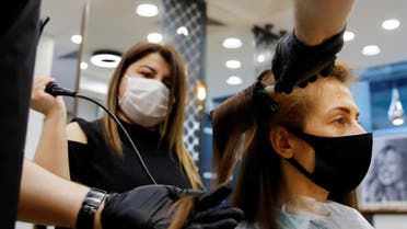 A hairdresser gives hair treatment to his customer Elena Kuznetsova, wearing a protective mask, on the first day of the reopening of his hair salon which was closed since March 21 amid the spread of the coronavirus disease (COVID-19), in Istanbul, Turkey, May 11, 2020. REUTERS/Umit Bektas