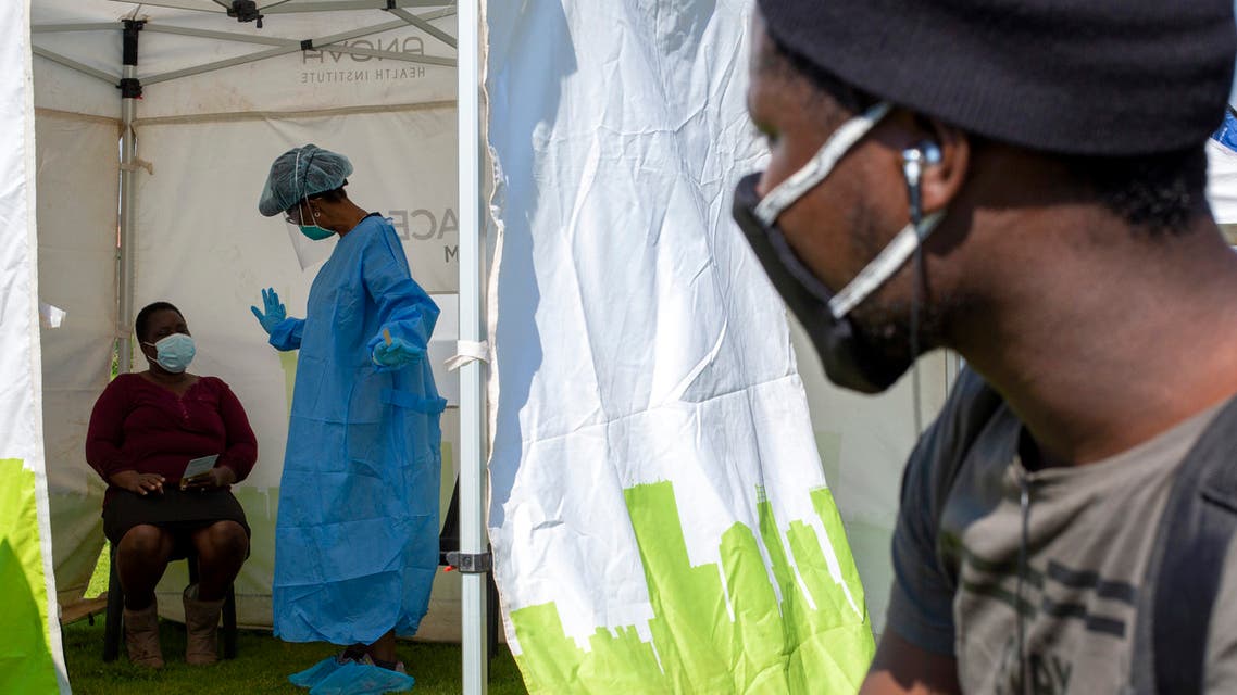 A man looks on through an opening of a tent as a woman watches the heath worker explain the process of collecting a sample for coronavirus testing in Johannesburg, South Africa on May 8, 2020. (AP)