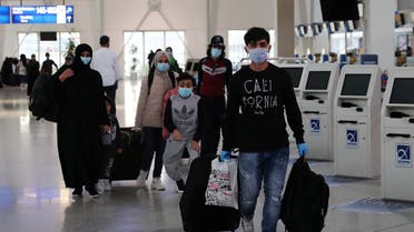 Refugees and migrants from overcrowded migrant camps who will be transferred to Britain where they will reunite with their families, wear protective face masks as a precaution against the coronavirus disease (COVID-19) at the check-in area at the Athens International Airport, Greece, May 11, 2020. REUTERS/Alkis Konstantinidis