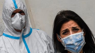 Rome mayor Virginia Raggi, wearing a face mask (R) and an employee of Rome's Municipal Environment Company (AMA), wearing protective overall and mask, attend the sanitation of the Santuario della Madonna del Divino Amore church on May 13, 2020 in the southern Castel di Leva district of Rome, during the country's lockdown aimed at curbing the spread of the infection caused by the novel coronavirus. The Italian Army, at the specific request of the Vicariate of Rome, started on May 13, 2020 the sanitation of Rome's churches through its specialized teams in the Chemical, Biological, Radiological and Nuclear (CBRN) fields. The activity, in collaboration with the municipality of Rome, will proceed according to a specific calendar for blocks of municipalities and provide for the sanitation of over 337 parish churches.