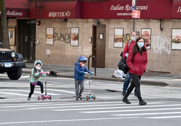 Children wearing face masks play on their scooters while their parents watch during the coronavirus pandemic on April 25, 2020 in New York City. (AFP)