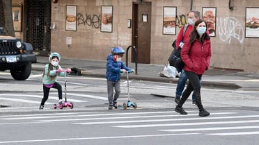 Children wearing face masks play on their scooters while their parents watch during the coronavirus pandemic on April 25, 2020 in New York City. (AFP)