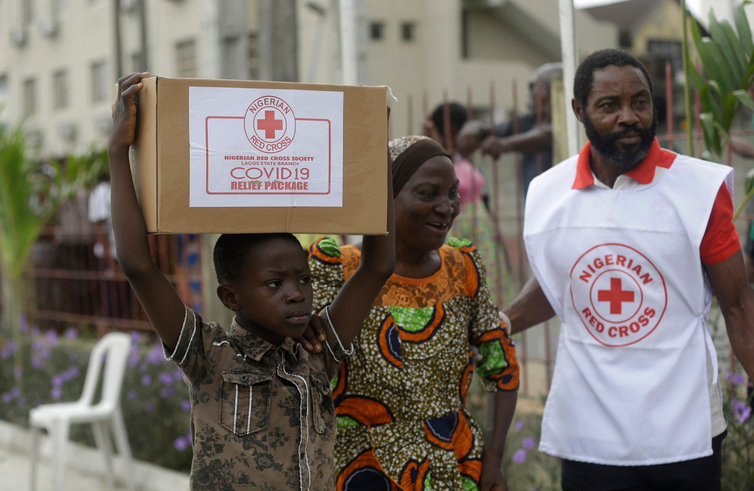 A child with his mother from Makoko Slum, carries their food parcel distributed by the Nigerian Red Cross, provided for those under coronavirus related movement restrictions, in Lagos, Nigeria on April 25, 2020. (AP)