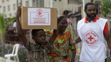 A child with his mother from Makoko Slum, carries their food parcel distributed by the Nigerian Red Cross, provided for those under coronavirus related movement restrictions, in Lagos, Nigeria on April 25, 2020. (AP)