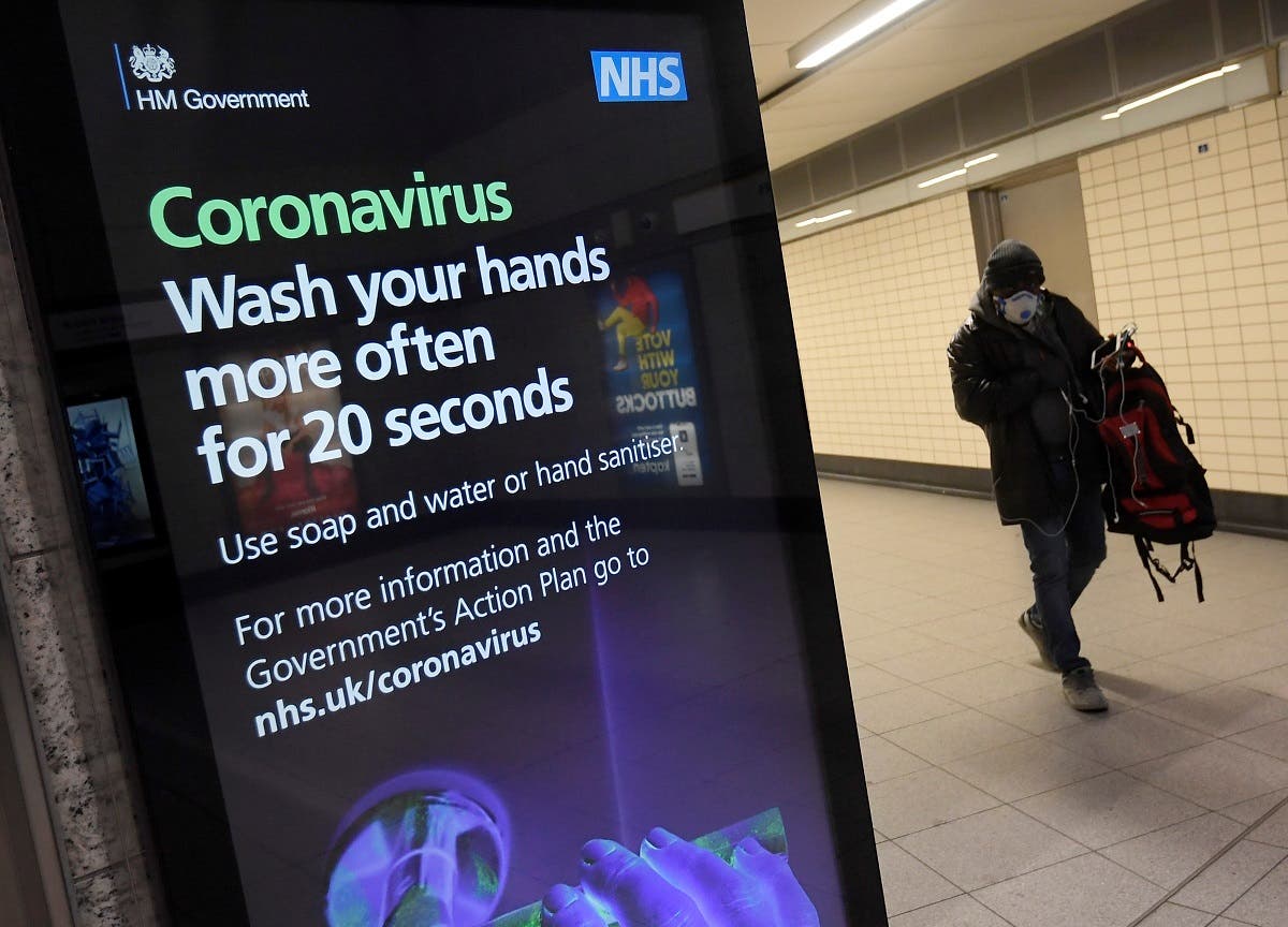 A man in a protective face mask walks past a British government public health campaign advertisement at Victoria underground station, as the number of coronavirus (COVID-19) cases grow around the world, London, Britain. (Reuters)