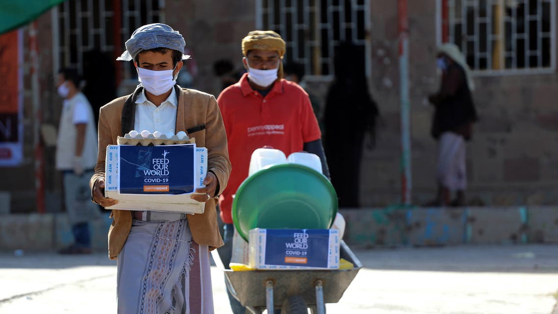 Men wearing protective masks receive humanitarian aid in Yemen's third city of Taez, on May 8, 2020, amid the novel coronavirus pandemic crisis. Yemen has suffered years of war that have driven millions from their homes and plunged the country into what the United Nations describes as the world's worst humanitarian crisis.