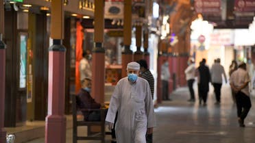 Men wearing face masks, due to the COVID-19 coronavirus pandemic, walk past jewellers' shops at the Dubai Gold Souk in the Gulf emirate. (AFP)