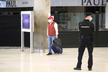 A passenger wearing a protective face mask walks past a National Police officer upon arriving at Adolfo Suarez Barajas Airport, after Spanish government announced that from May 15th all people entering Spain will have to go under quarantine for two weeks, amid the coronavirus disease (COVID-19) outbreak in Madrid, Spain, May 12, 2020. (Reuters)