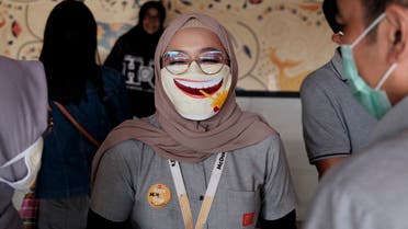 An employee wearing a face mask as a precaution against the new coronavirus outbreak shares a light moment with colleagues at a McDonald's restaurant in Jakarta, Indonesia. (AP)