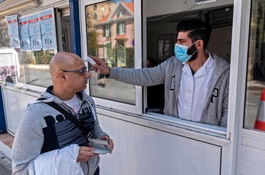 In this file photo taken on March 04, 2020, a Cypriot medic checks the temperature of a man crossing the Ledra Palace checkpoint in Nicosia. (File photo: AFP)