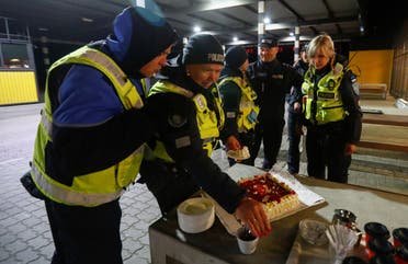 Estonian police and border guard officers pick pieces of cake at border crossing point between Estonia and Latvia on May 15, 2020. (Reuters)