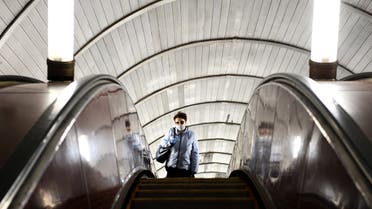AFP - A woman wearing a face mask and gloves rides an escalator at Savyolovskaya metro station on the first day of mandatory use of masks and gloves on Moscow public transport, in Moscow on May 12, 2020, amid the coronavirus pandemic.