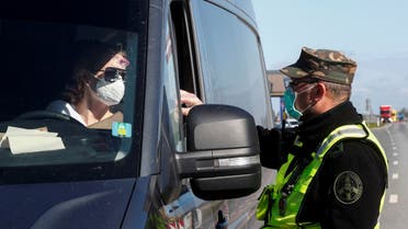 A Lithuanian border guard checks documents of a person crossing the Latvian-Lithuanian border, as travel restrictions for residents are lifted during the coronavirus outbreak, in Salociai border crossing point, Lithuania May 15, 2020. (Reuters)