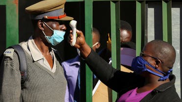  A person checks a policeman's temperature during a nationwide lockdown to help curb the spread of the coronavirus in Harare, Zimbabwe, on May 14, 2020. (Reuters) 