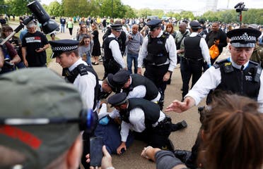 A protester is detained by police officers during a demonstration in Hyde Park, following the outbreak of the coronavirus, in London, on May 16, 2020. (Reuters) 