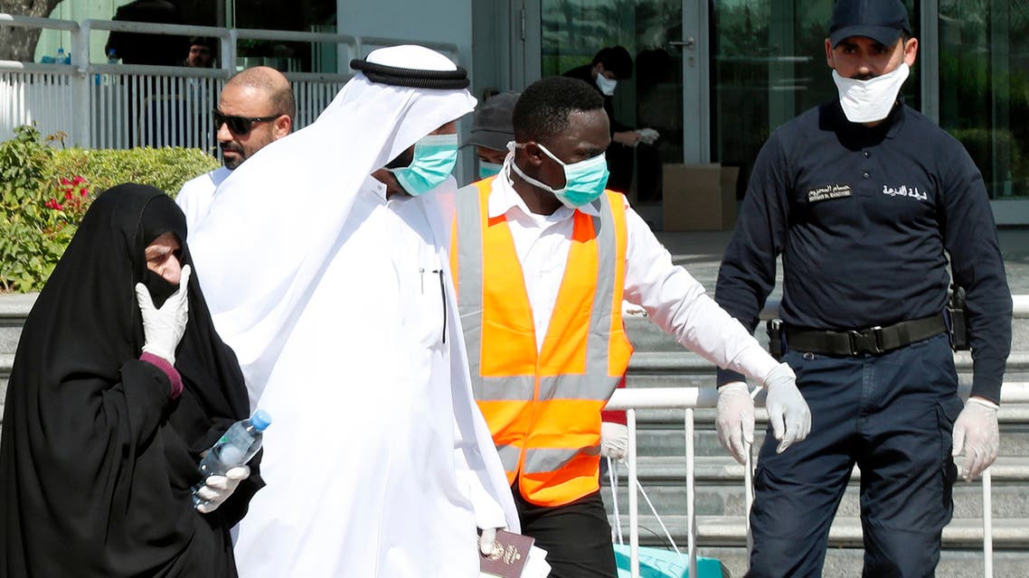 Qatari police stand outside a hotel in Doha as a medical worker walks alongside people wearing protective masks over fears of coronavirus, on March 12, 2020. (AFP)