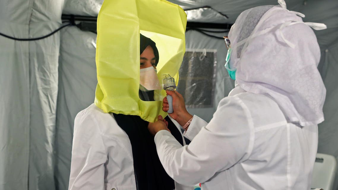 A medical worker assists another to dress up in protective gear at a tent in a field hospital to treat coronavirus patients in Mecca in Saudi Arabia, May 13, 2020. (AFP)