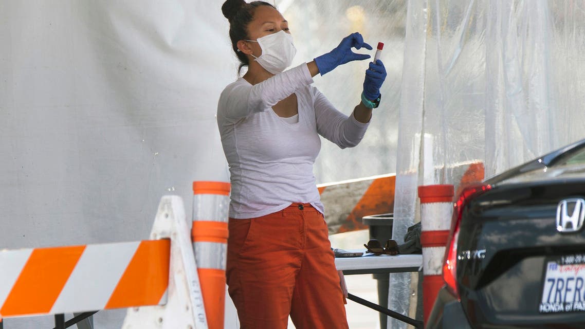 A member of the staff gives instructions on how to use a Covid-19 self-test kit to a member of the public at a drive-thru test site at the Rose Bowl in Pasadena, California, on May 13, 2020. (AP)