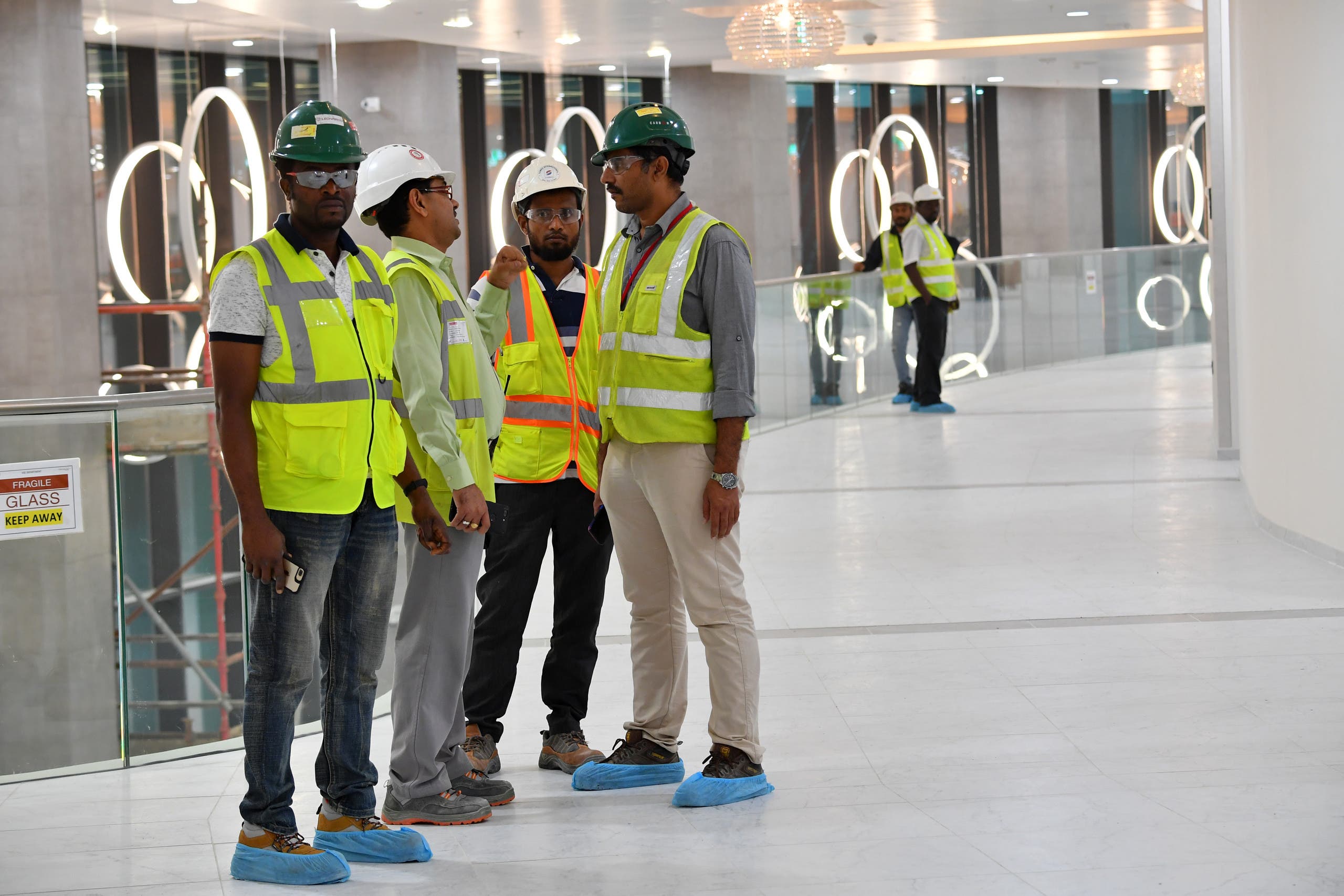 This picture taken on December 17, 2019 shows construction workers speaking together inside Qatar's new al-Bayt Stadium in the capital Doha, which will host matches of the FIFA football World Cup 2022. (AFP)