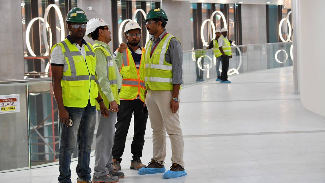 This picture taken on December 17, 2019 shows construction workers speaking together inside Qatar's new al-Bayt Stadium in the capital Doha, which will host matches of the FIFA football World Cup 2022. (AFP)